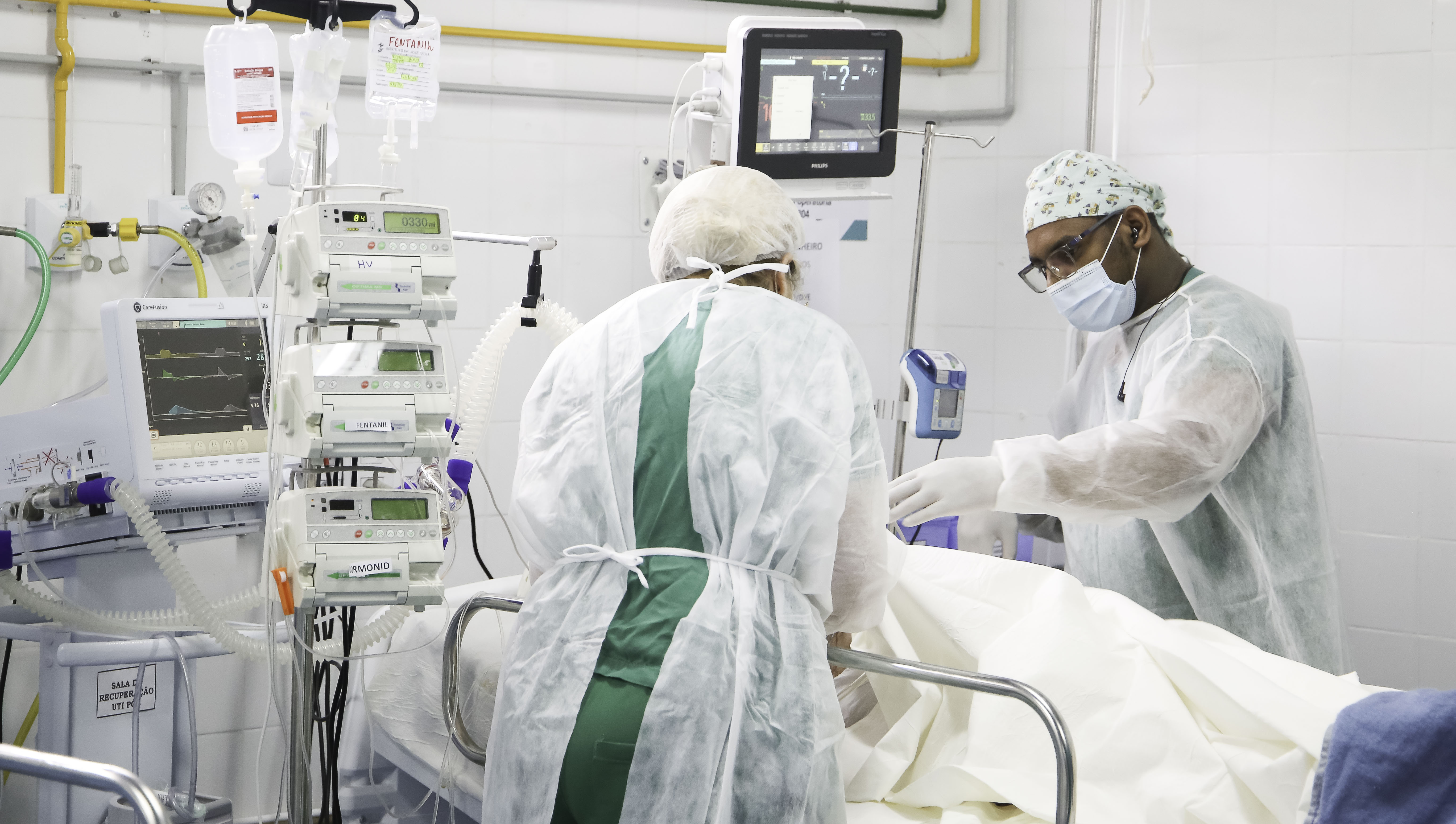 a foto mostra um médico e uma enfermeira junto a um leito de UTI